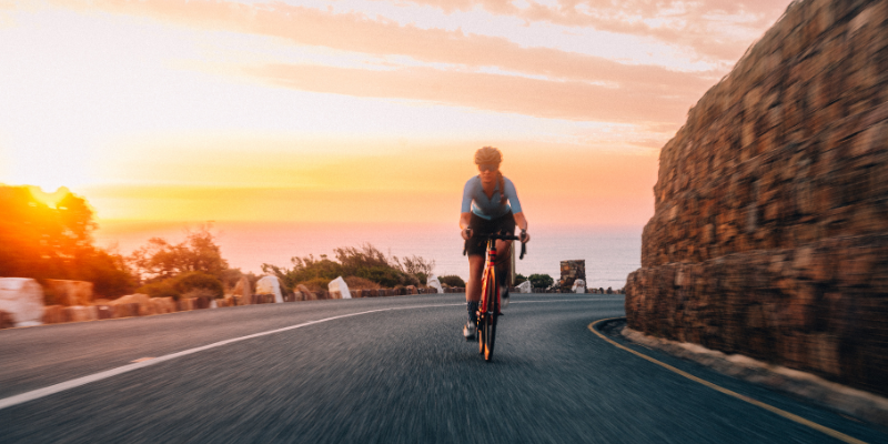 Cyclist riding at sunset on a coastal road